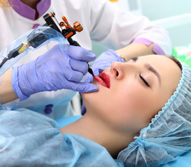 Cosmetologist making permanent makeup on woman's face