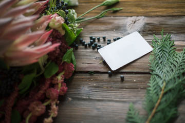 Florist workplace: visit card and flowers and accessories on a vintage wooden table. soft focus