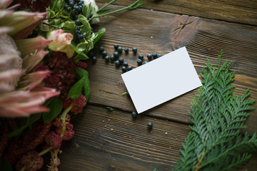 Florist workplace: visit card and flowers and accessories on a vintage wooden table. soft focus