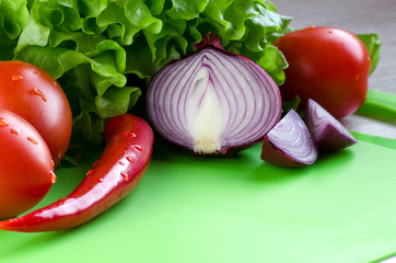 Fresh vegetables on the kitchen Board on green background