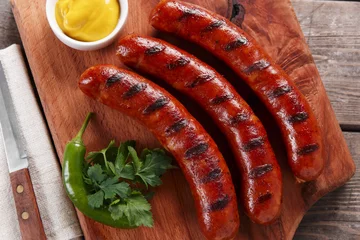 Photo sur Plexiglas Grill / Barbecue Grilled sausage on a wooden board with sauce and vegetables