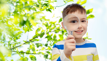 happy little boy looking through magnifying glass