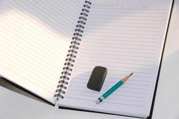 Close up Green Pencil and black eraser placed on a notebook