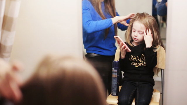 hairdresser combing her hair of cute little girl