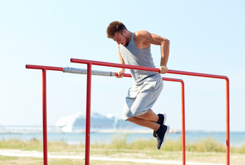 young man exercising on parallel bars outdoors