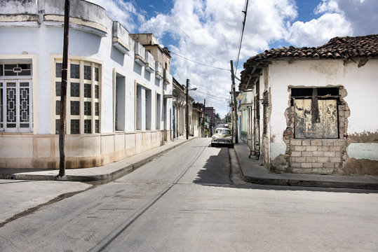 Kuba, Santa Clara: Leere Straßenkreuzung mit parkendem Oldtimer im Zentrum der kubanischen Kleinstadt 