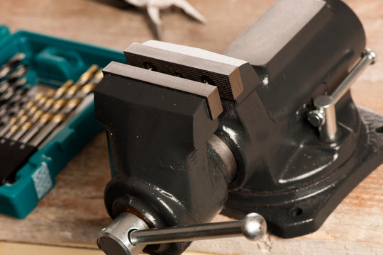Closeup of vice tool clamping device on wooden background.