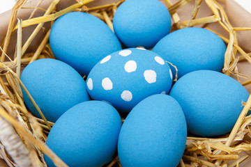 Blue easter eggs in a basket on a white wooden table