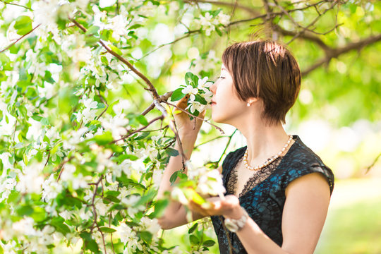 Portrait of young woman  in the flowered garden in the spring time. Almond flowers blossoms. 