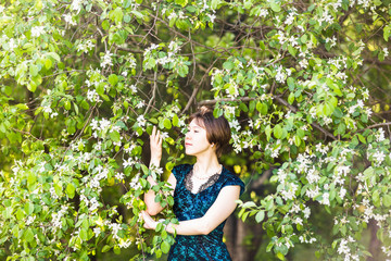 Portrait of young woman  in the flowered garden in the spring time. Almond flowers blossoms. 