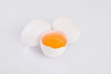 Whole and broken raw white eggs on white background