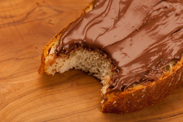 Slice of bread with sweet chocolate nougat spread, bite.