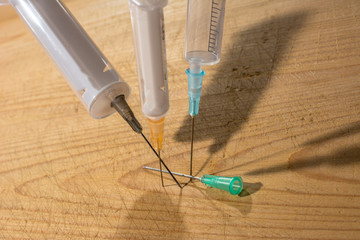 pocketed needles, syringes on a wooden background, close-up, driven into the board - obrazy, fototapety, plakaty
