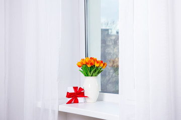 bunch of beautiful tulips and gift box on a window sill