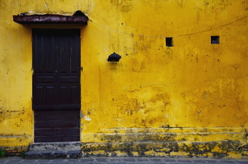 Naklejka premium Old and grungy yellow wall with wooden door