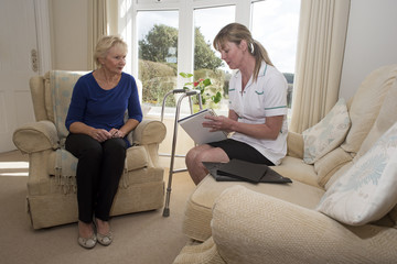 Obraz premium Nurse on a home visit talking with an elderly female patient