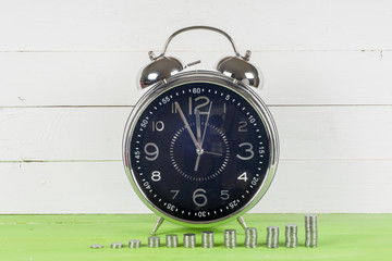 Antique clock and coins on wooden table on bright background