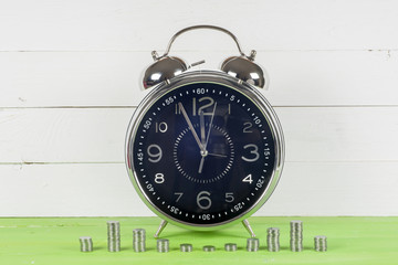 Antique clock and coins on wooden table on bright background