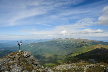 Obraz premium young woman practices yoga on a mountain top, Carpathian mountains