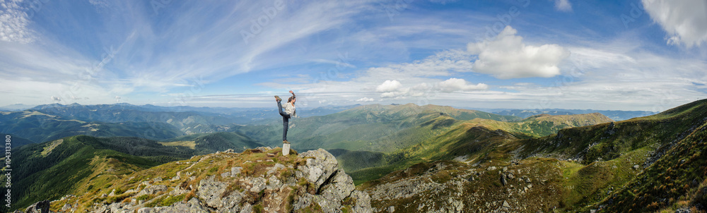 Wall mural young woman practices yoga on a mountain top, carpathian mountains