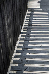 Fototapeta na wymiar Schatten eines Geländers auf Holzsteg