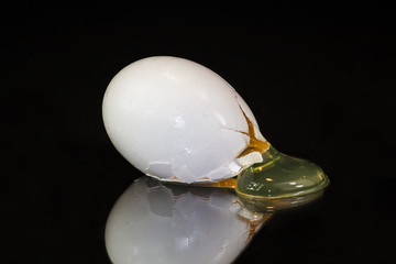 broken organic white egg on black background