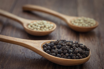 Black pepper and white pepper on wooden spoon