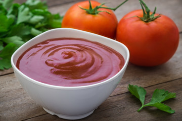 Tomato sauce or ketchup in bowl and fresh tomatoes