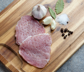Raw meat on a wooden cutting board with spices