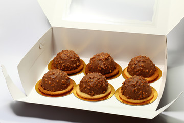 Cakes in box. Six cakes in a paper box over white background