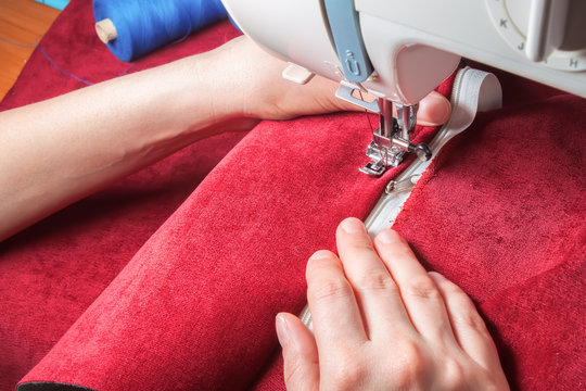sewing machine, red fabric and women's hands