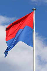 Flag of the State and Republic of Canton Ticino, Switzerland, flapping in the wind against blue skies and white clouds