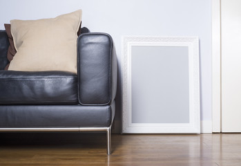 A white Baroque picture frame sitting on a polished wooden floor.