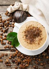 Close-up of coffee cup with roasted coffee beans on wooden backg