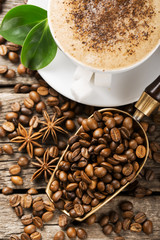 Close-up of coffee cup with roasted coffee beans on wooden backg