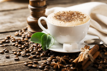 Close-up of coffee cup with roasted coffee beans on wooden backg