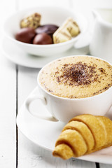 Hot cappuccino and pastries on white wooden boards