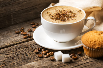 Close-up of coffee cup with roasted coffee beans on wooden backg