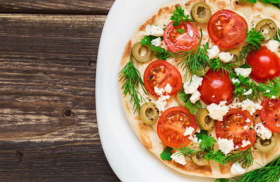Pita with hummus, cheese, cherry tomatoes, olives and greenery