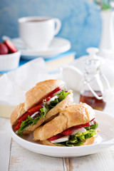 Croissant sandwich with brie, salad and strawberry