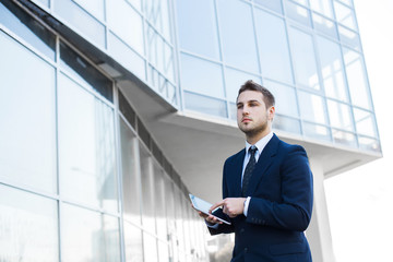 Businessman using a digital tablet computer, standing in front of his office.