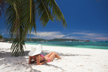 young girl resting on the beach under a palm tree
