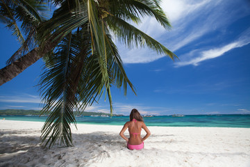 Fototapeta na wymiar young girl resting on the beach under a palm tree