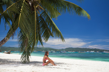 young girl resting on the beach under a palm tree