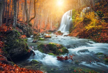 Fototapeten Schöner Wasserfall am Gebirgsfluss im bunten Herbstwald mit roten und orangefarbenen Blättern bei Sonnenuntergang. Naturlandschaft © den-belitsky