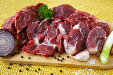Raw beef on wooden board with garlic and onions