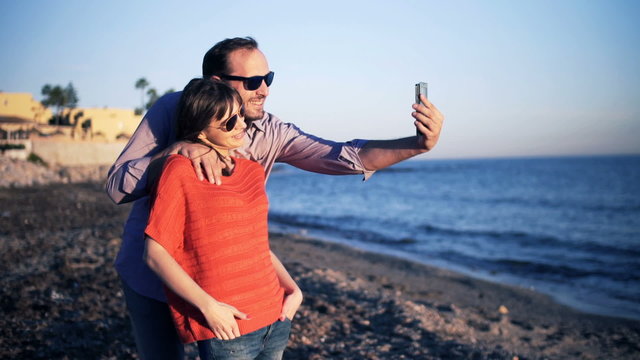 Young, happy couple taking selfie photo on beach

