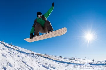Crédence de cuisine en verre imprimé Sports dhiver Snowboarder jumping against blue sky