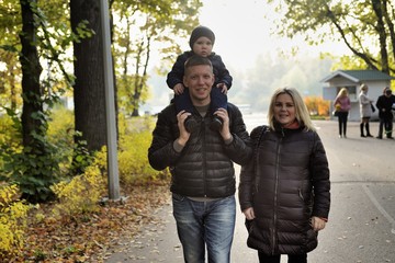 Fototapeta premium Pregnant young woman walking in autumn park with her husband and child