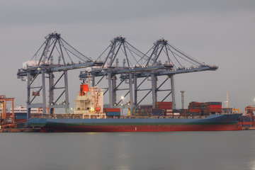 Large cargo ship with containers loading by crane at port